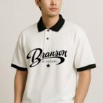 Step up your casual game with the Heritage Script Polo Shirt, a premium piece that blends classic style with bold graphics. This polo is crafted from a comfortable, breathable knit fabric in a crisp white color. The design is elevated by striking black contrast details on the collar, sleeve cuffs, and the prominenttwo-button placket and a relaxed fit, this shirt offers effortless style for a variety of occasions—from a casual Friday at the office to a weekend outing. It's the perfect choice for those who appreciate high-quality comfort and a distinctive, vintage-inspired look. Available in sizes S to XXL.